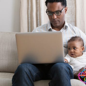 Father working on laptop while taking care of a baby.