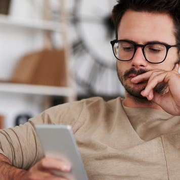 Man looks at cell phone, thinking