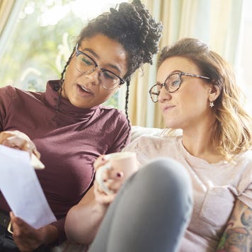 Same sex couple sits on the couch together reviewing their auto insurance policy.