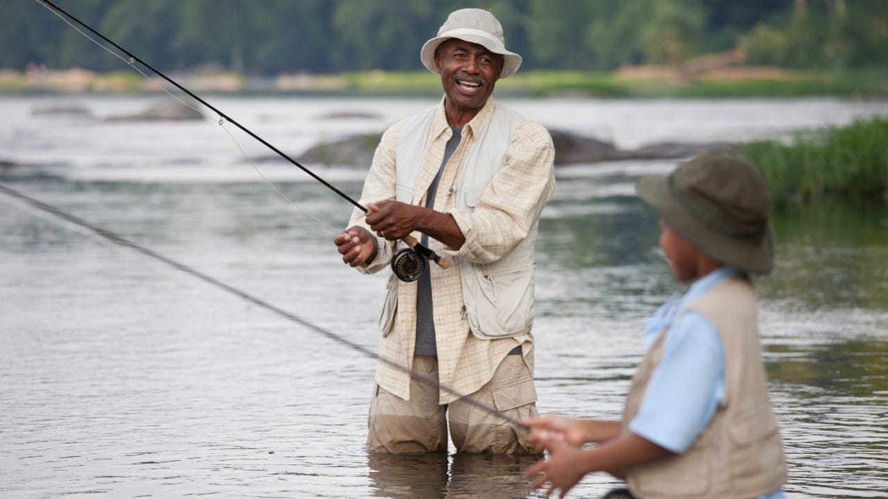 A grandfather and grandson fish in a lake