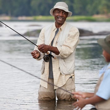 A grandfather and grandson fish in a lake