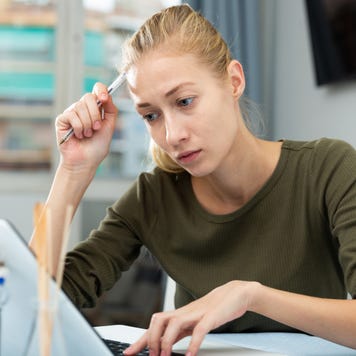 Woman looks concerned while working on laptop