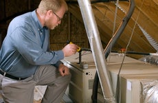 A home inspector assesses the attic in a home.