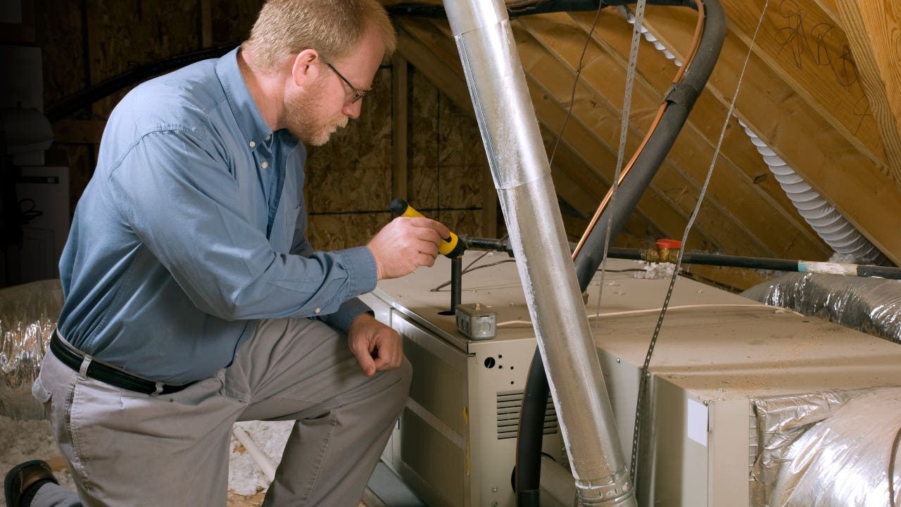 A home inspector assesses the attic in a home.