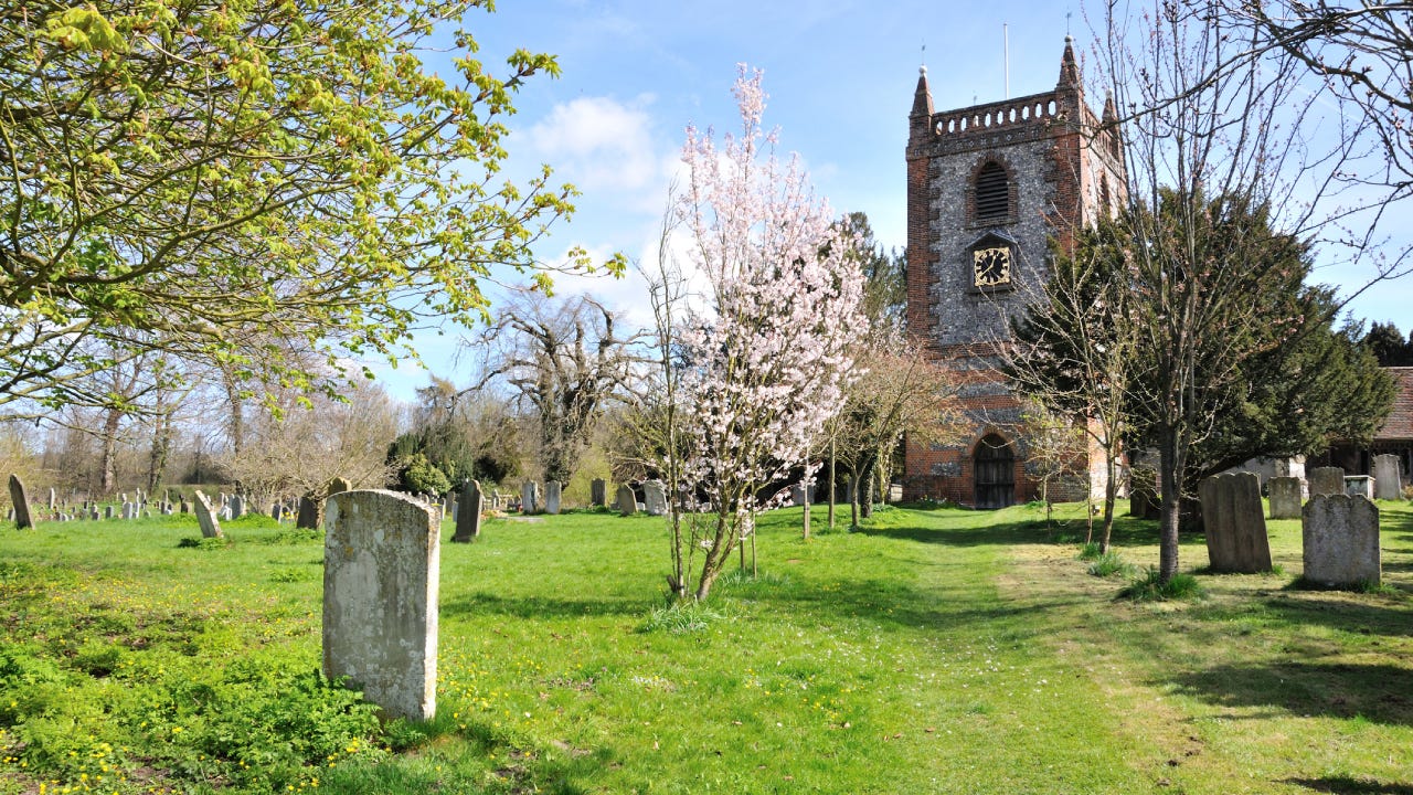 A sunny day at an old cemetery outside of an old stone chapel.