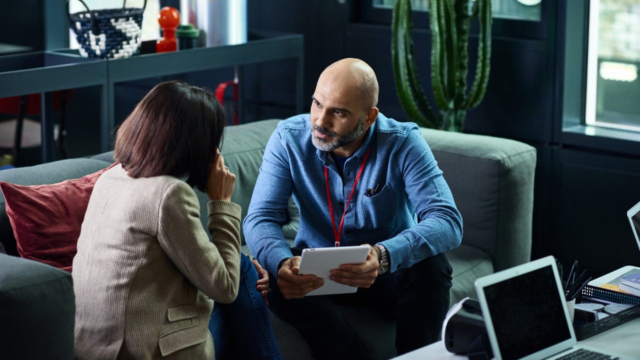 A financial advisor sits with a client going over some records.
