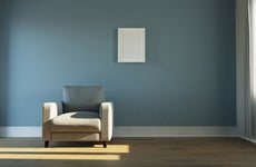 A shot of an empty living room with a blue wall and a white chair.