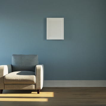 A shot of an empty living room with a blue wall and a white chair.