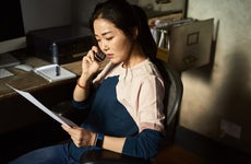 An Asian woman sits down on the phone after receiving her claims check.
