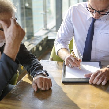 A man sits with his financial advisor looking over some documents.