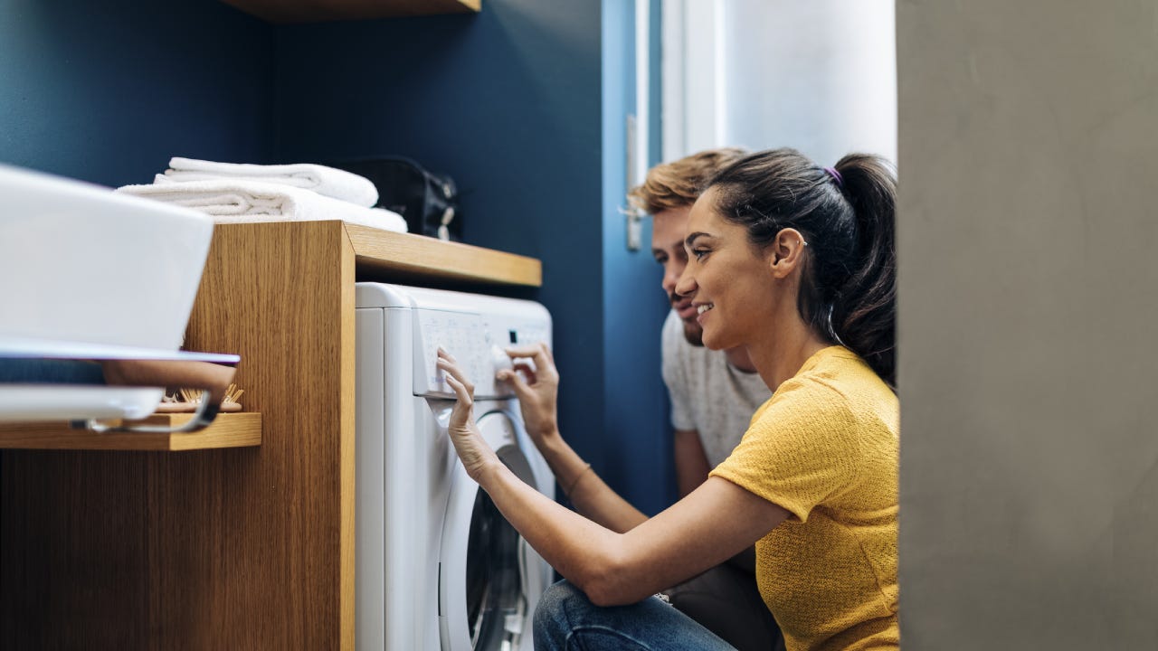 A woman and her husband are using a brand new washer machine.