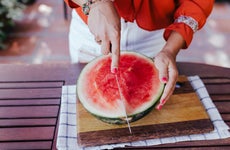 A woman cuts a watermelon in half