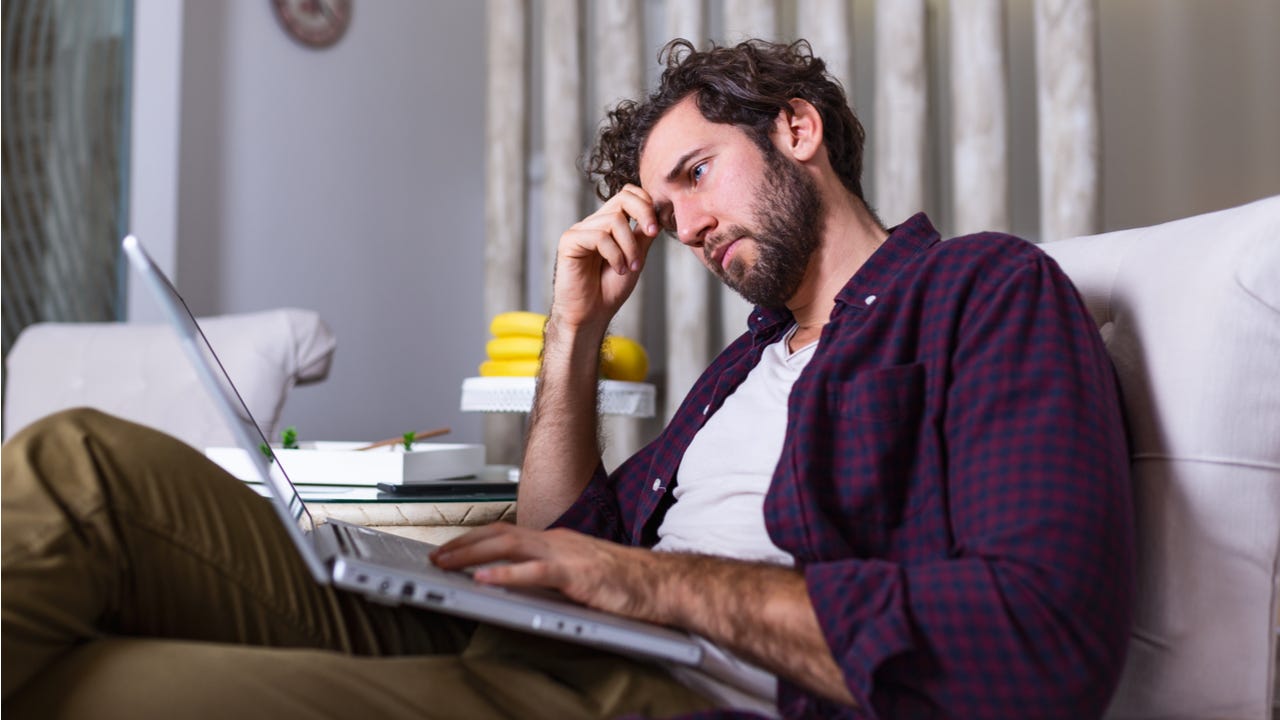 Stressed man looks at laptop