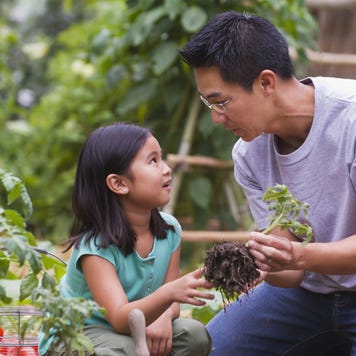 An Asian father is gardening with his little daughter.