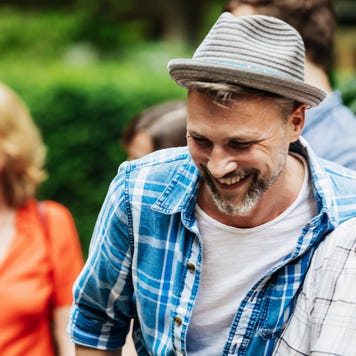 An adult son is spending time with his father out in the backyard during a family cookout.