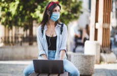 College student sits outside while wearing a mask