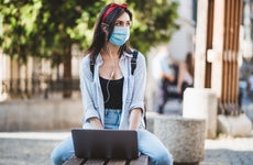 College student sits outside while wearing a mask