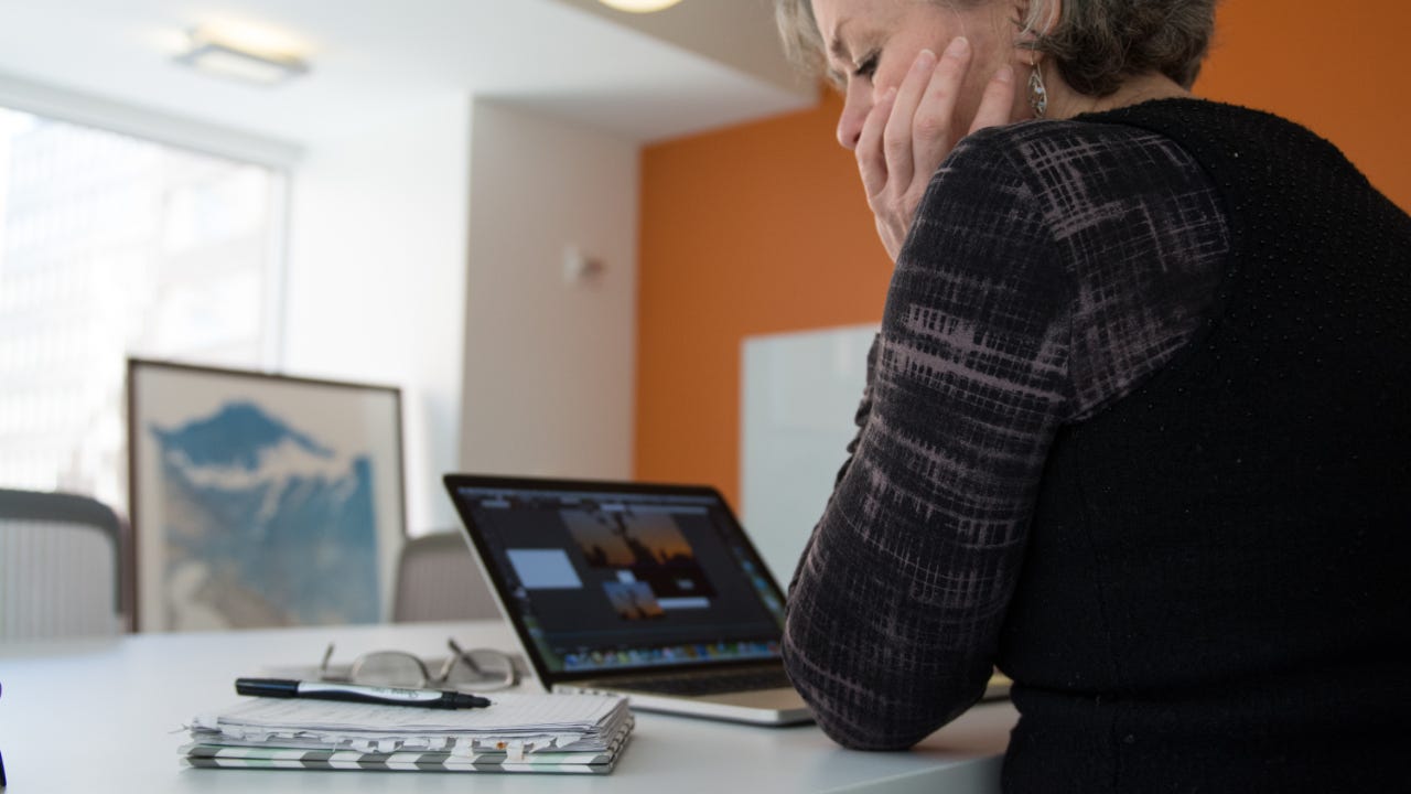 An older woman works on her laptop.