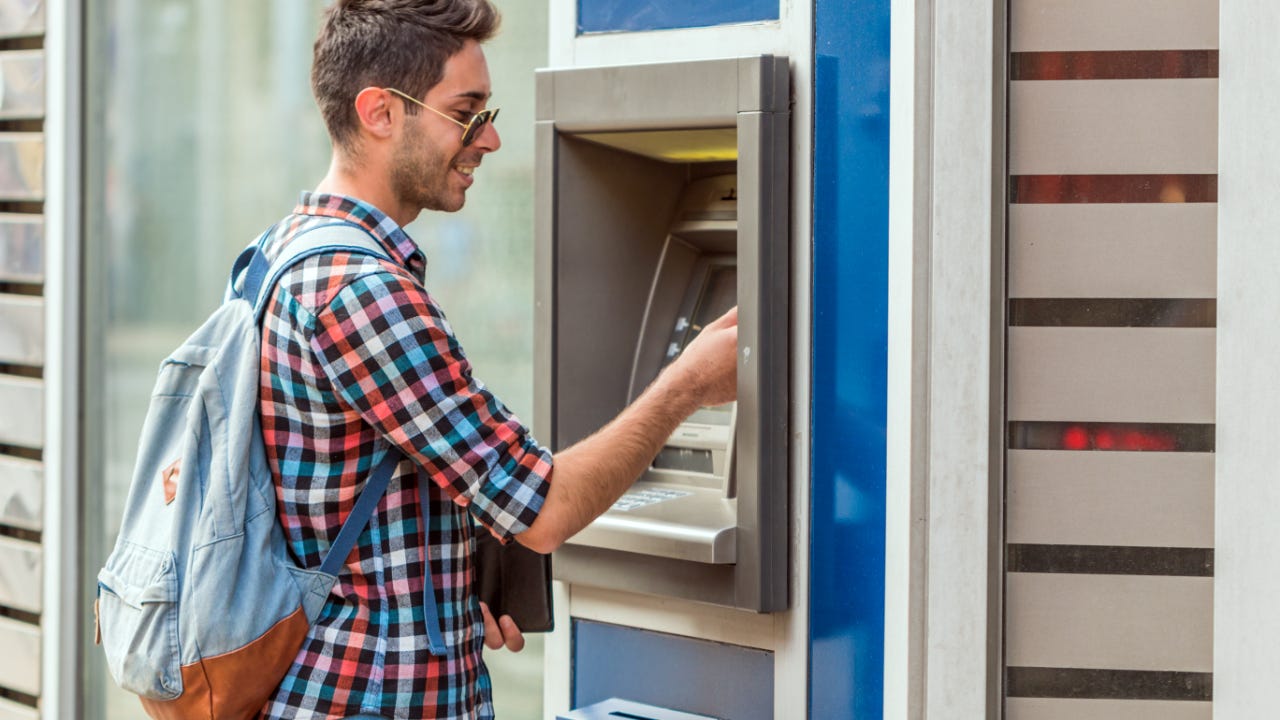 A young man uses an ATM.
