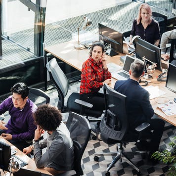 An office area full of people sitting back to back at their computers.