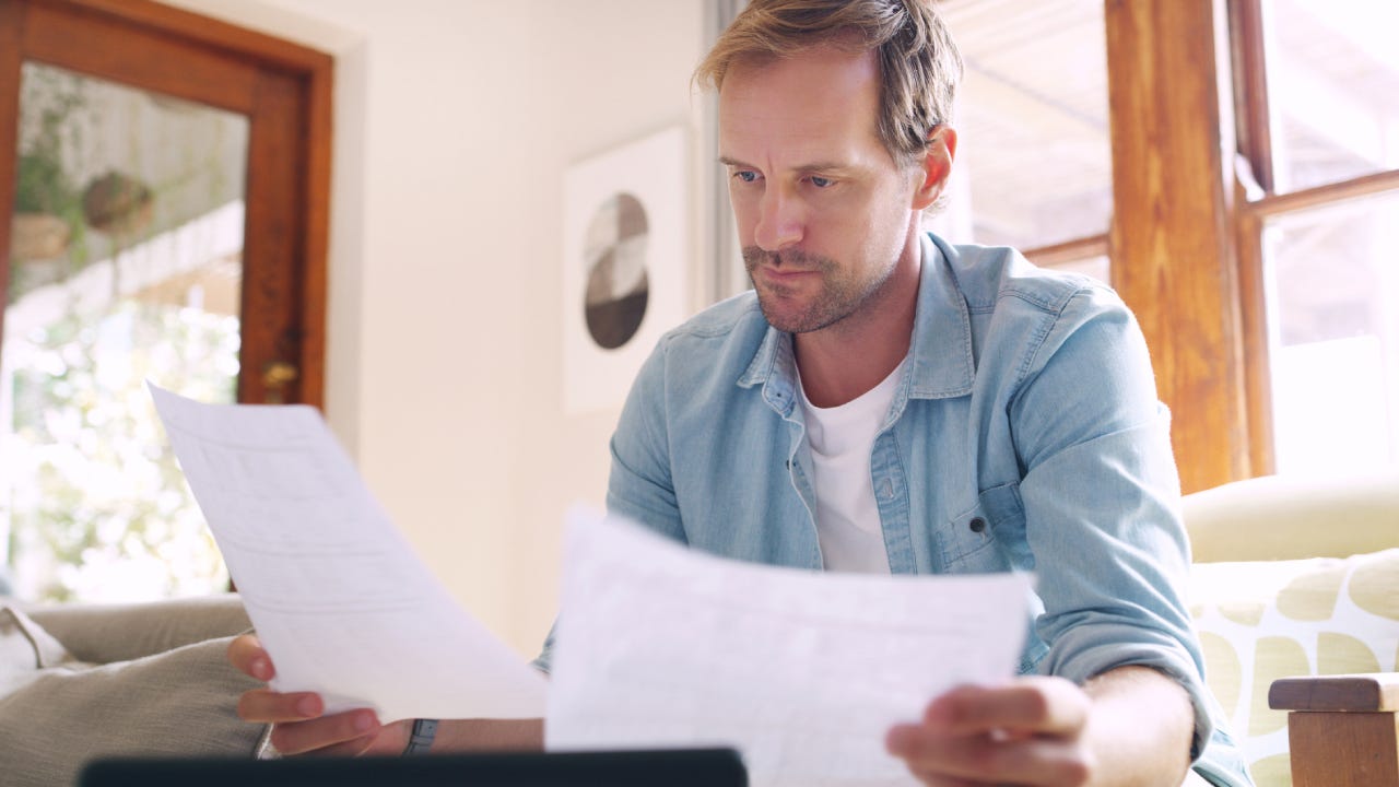 A man looking at some insurance forms. He looks concerned.