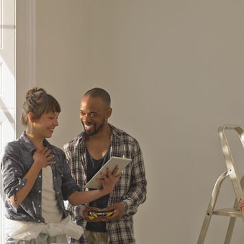 A young couple is standing together in their unfinished living room.