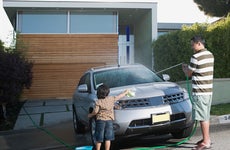 A father and child washing their car in the driveway.