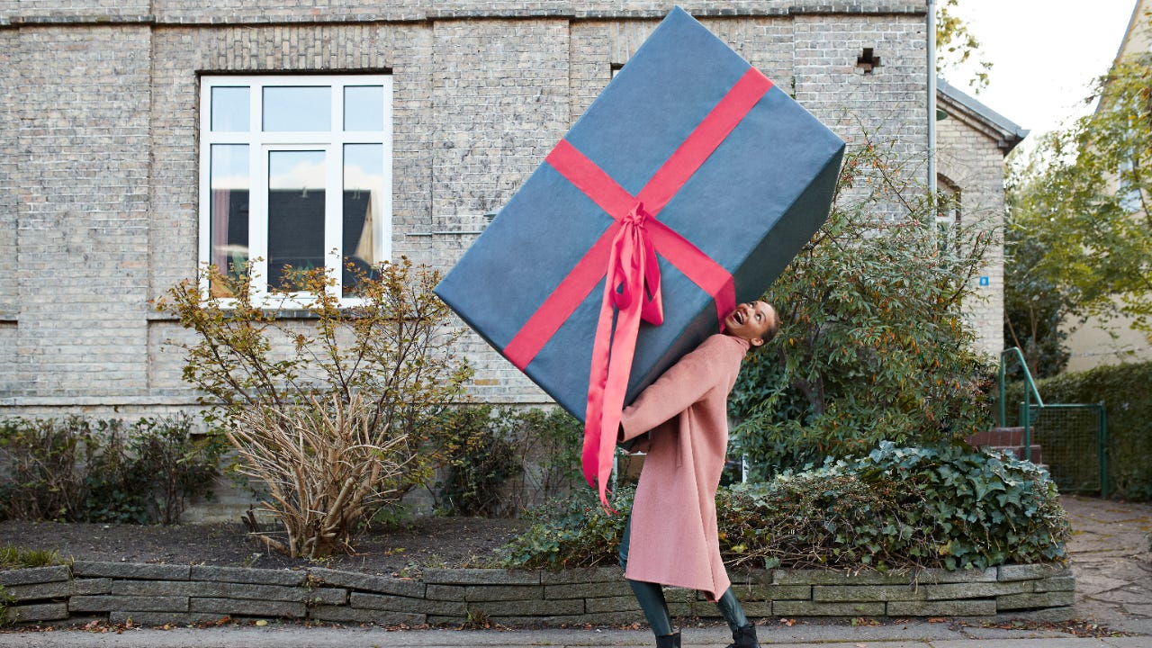 A woman carries an oversized present