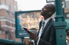 A black businessman in New York City listens to a podcast while walking