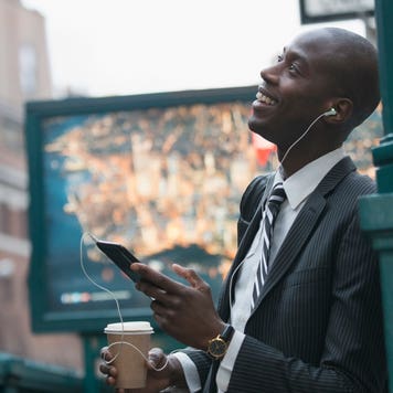 A black businessman in New York City listens to a podcast while walking