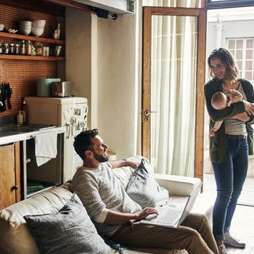 Person holding baby looking at person sitting on couch