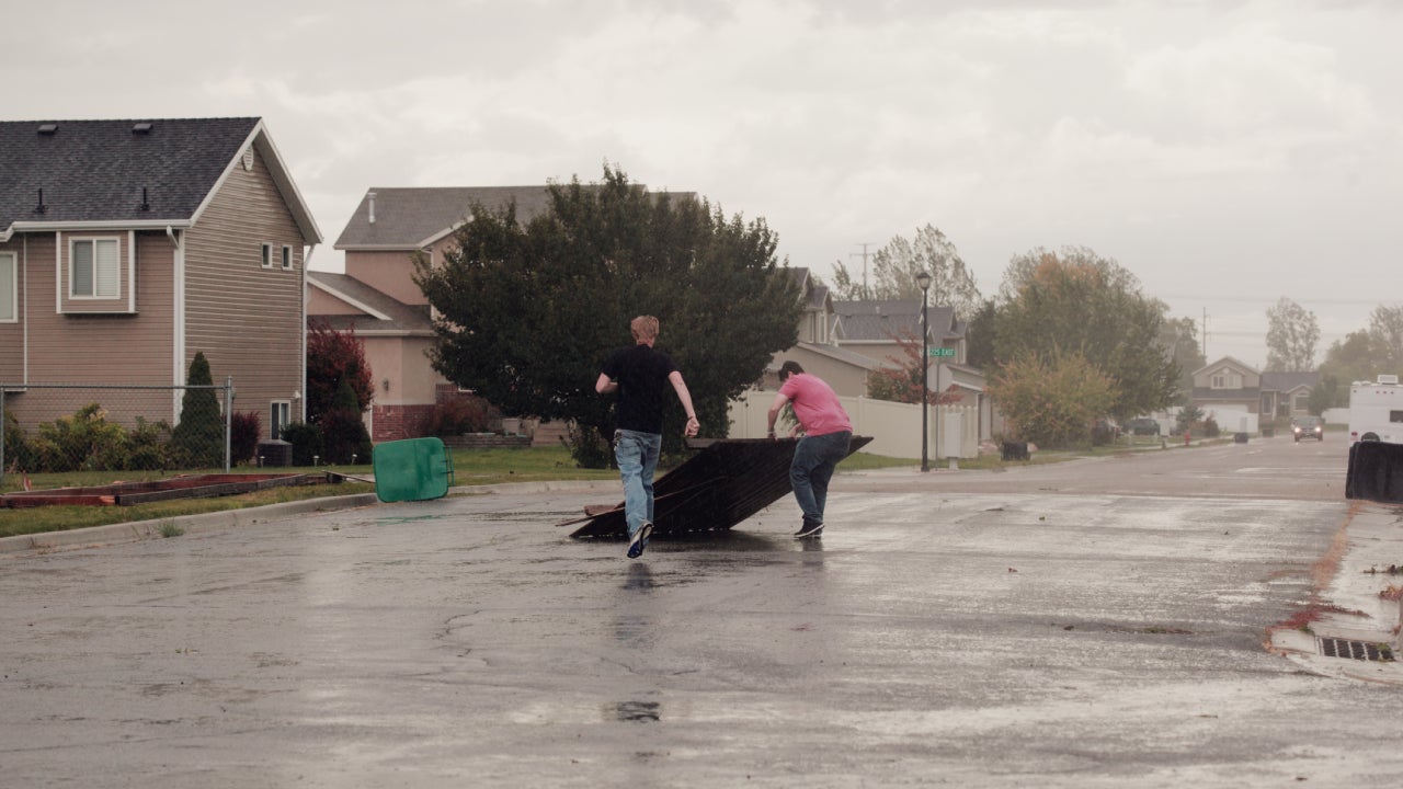 Two men are removing debris from the street after a tornado.