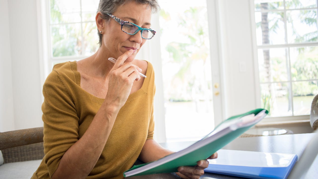 Woman reading folder at desk in living room