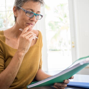 Woman reading folder at desk in living room