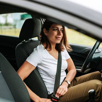 woman in car putting on seat belt