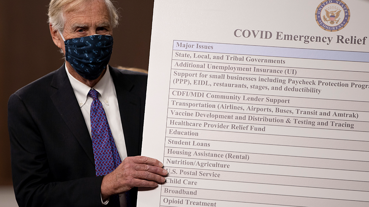 Sen. Angus King (I-ME) sets up a sign alongside a bipartisan group of Democrat and Republican members of Congress as they announce a proposal for a Covid-19 relief bill.
