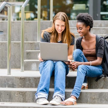 Two college students sit on steps outside