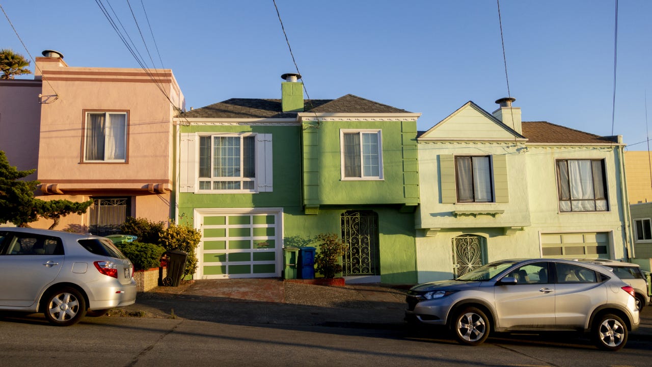 Green house with a car in front of it on the sloping streets of San Francisco.