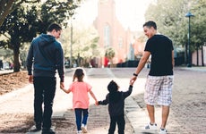 A gay couple walks with their kids.