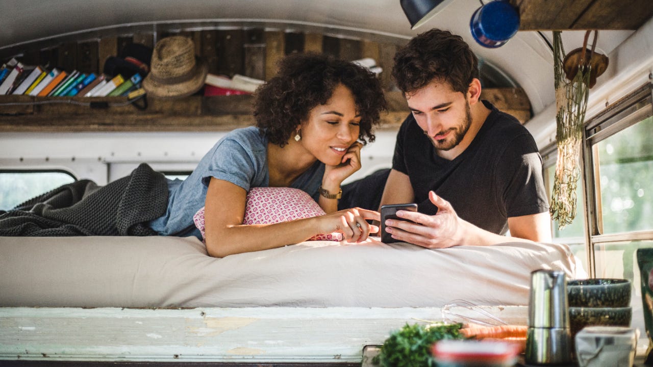 A couple looks at a phone in their camper van