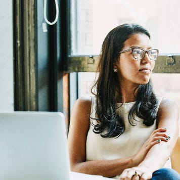 Businesswoman looking out window while seated at desk in office