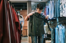 young person holding up a shirt while shopping in a store
