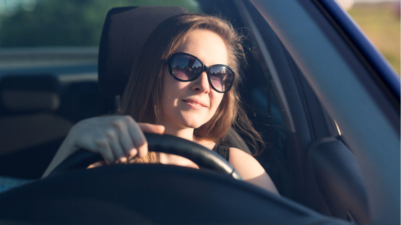 Woman wearing sunglasses drives a car