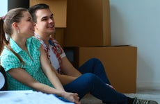 Couple sits in new home with moving boxes