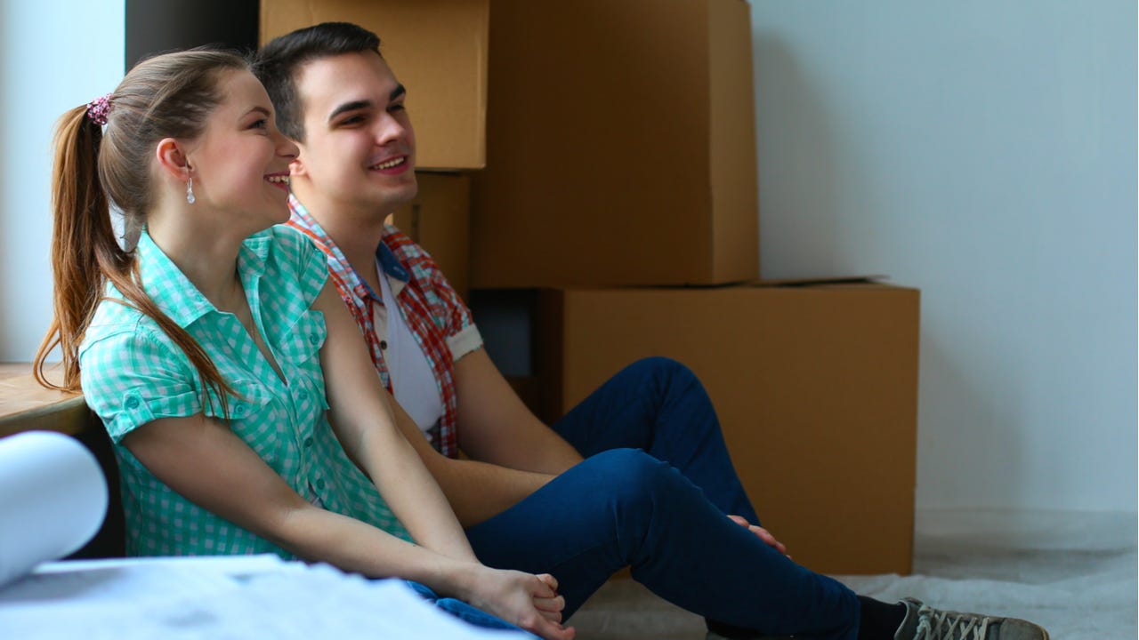 Couple sits in new home with moving boxes