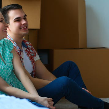 Couple sits in new home with moving boxes