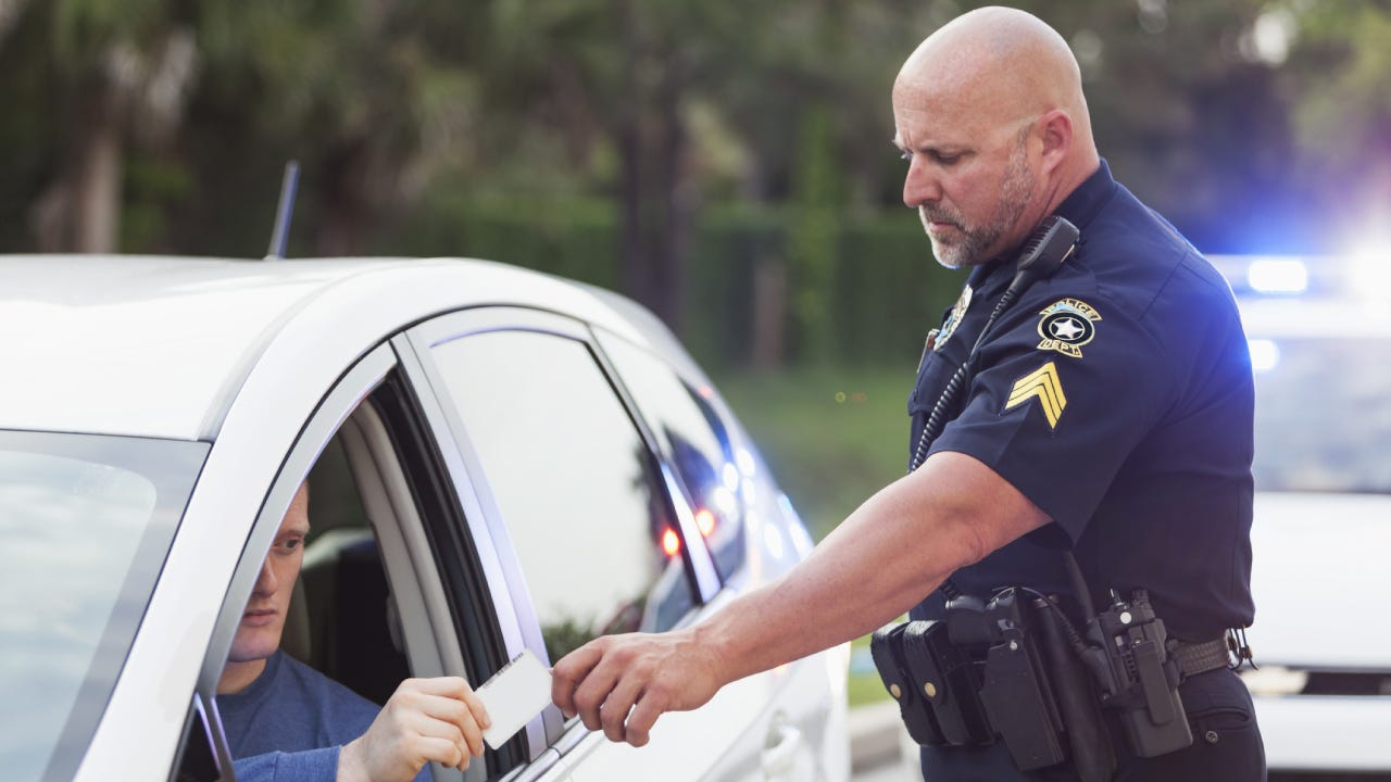 A cop at a traffic stop getting necessary information from a driver he stopped.