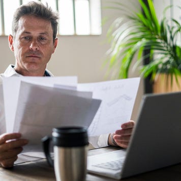 Focused businessman using laptop and reviewing documents at desk