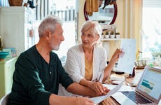 An older couple discusses finances at their kitchen table