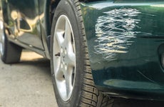 Close-up of a green car with a scratched fender where a white car hit it.